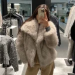 Woman trying on a plush faux fur coat in a fashion store, showcasing winter outerwear.