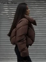 Stylish woman wearing a warm puffer jacket against metallic shutter background.